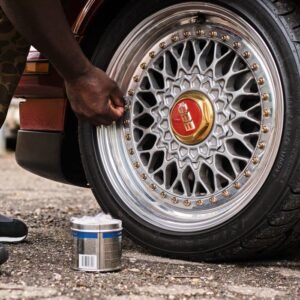 Man polishing a classic car's wheel rim with care in a garage setting.