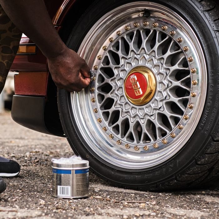 pexels photo 17623847 17623847 Man polishing a classic car's wheel rim with care in a garage setting.