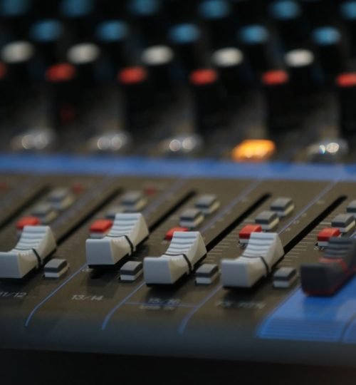 Why VTAR Close-up of an advanced audio mixing panel with slide controls and knobs in a studio setting.