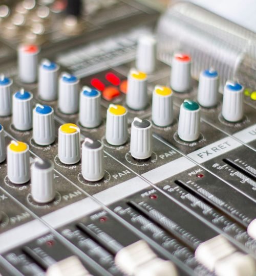 Why VTAR Detailed close-up of an audio mixing console with colorful knobs and sliders for sound control.