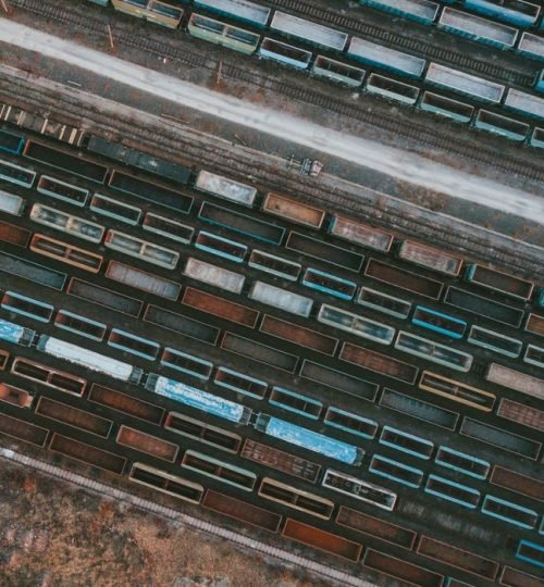 Why VTAR Drone shot of colorful cargo trains lined up in a rail yard, showcasing industrial logistics.
