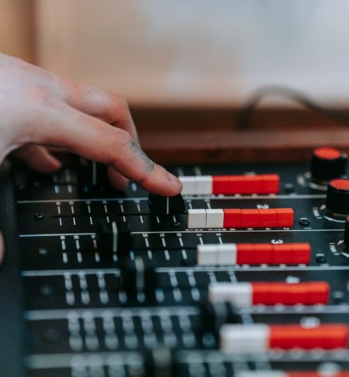 Why VTAR Hand adjusting mixer controls in a sound studio, showcasing precision and audio engineering.